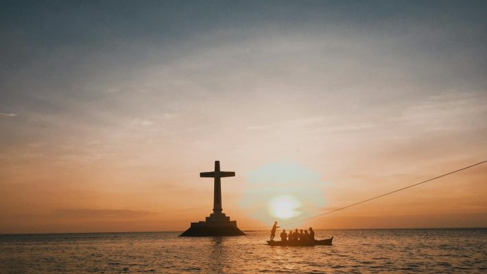 photo of cross in an ocean during dawn